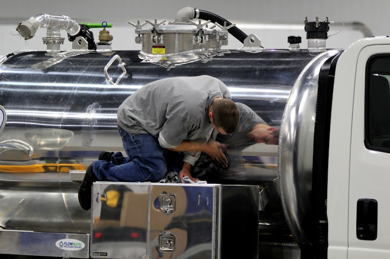 Mark Flahaut of K-Rae Transportation polishes the side of a vacuum truck on Tuesday during WWETT Show setup.