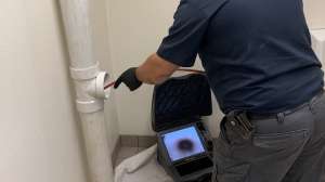 Technicain using sewer camera through clean out WEB