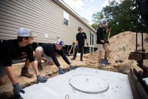Young workers place cement septic tank